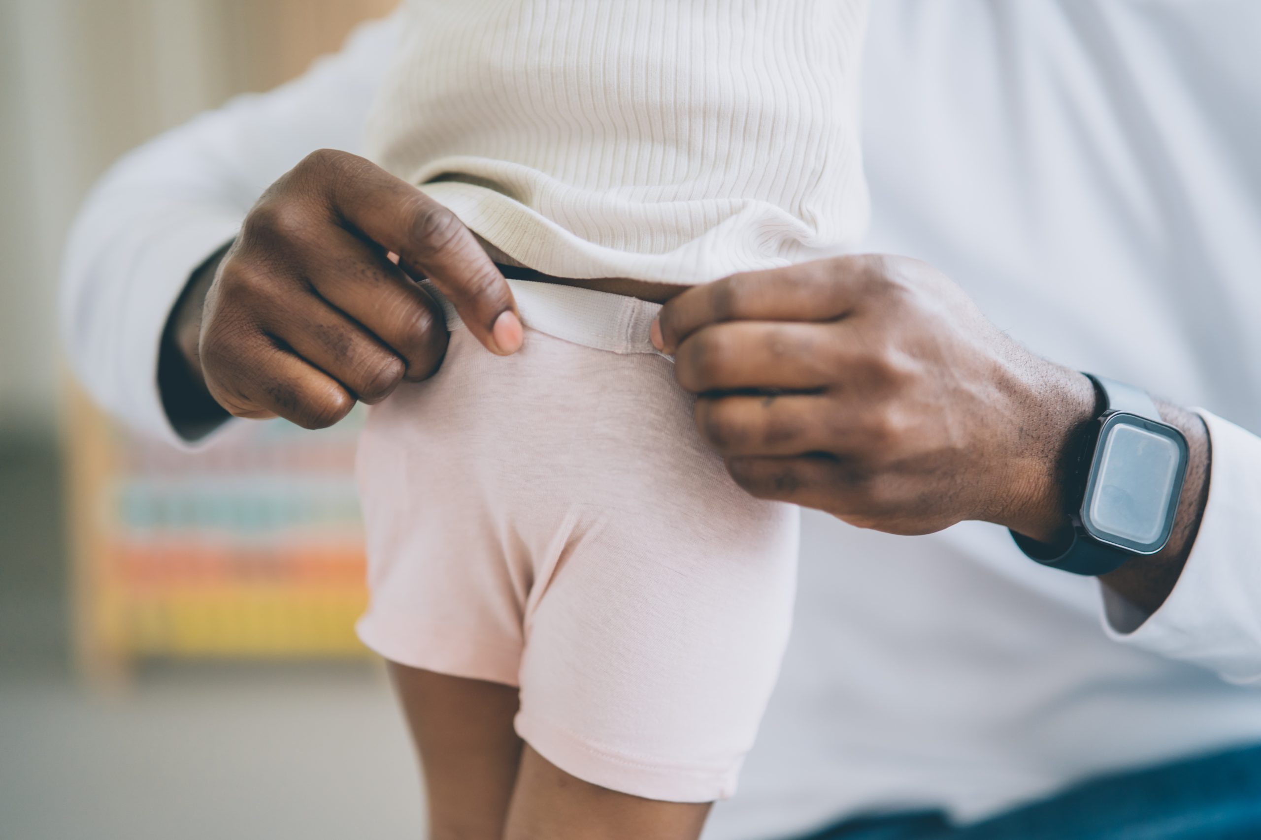 Pull up pants A father helps his little daughter during potty training by pulling up her pants. Comfortable clothes for child during potty training.