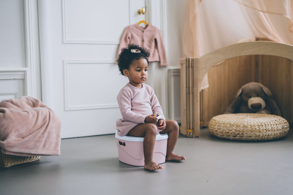 Child sitting on potty with correct toilet posture during potty training / toilet training. The constipation or poo problems would no longer continue if child sits on toilet correctly.