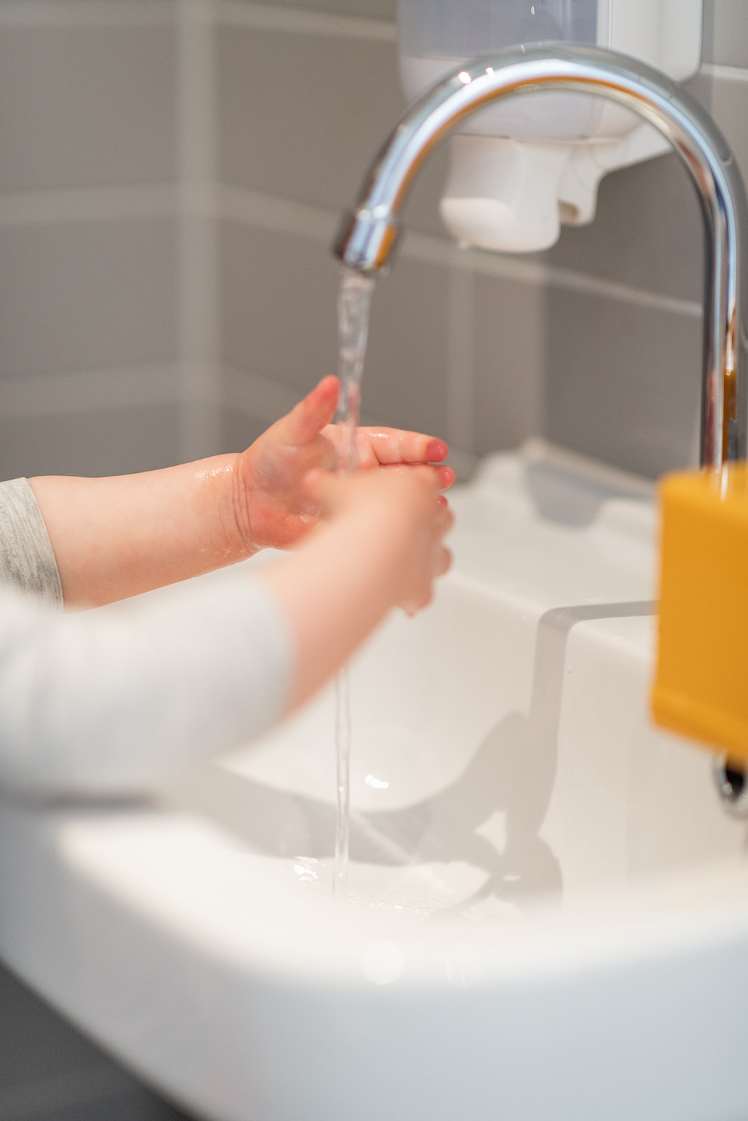 A young child standing on a stool in front of a bathroom sink, diligently washing their hands with soap and water after using the potty during potty training/ toilet training. The child is focused and engaged in the process, demonstrating good hygiene practices. hand washing is good for health
