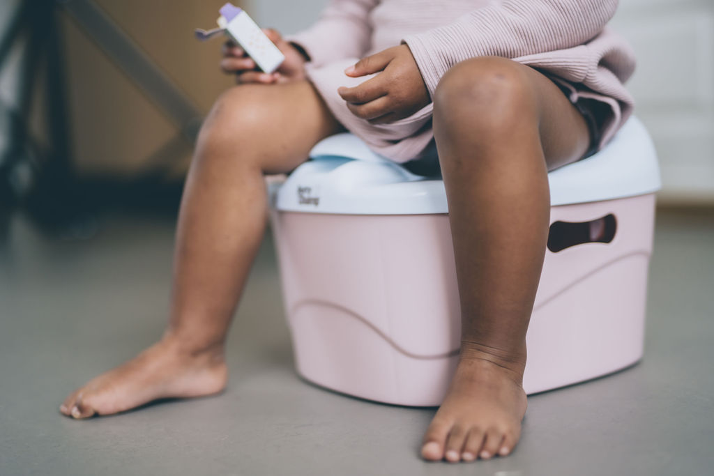 7 Things Every Parent Ought to Know About Potty Training legs of chid sitting on potty holding raisins. Potty Training app.