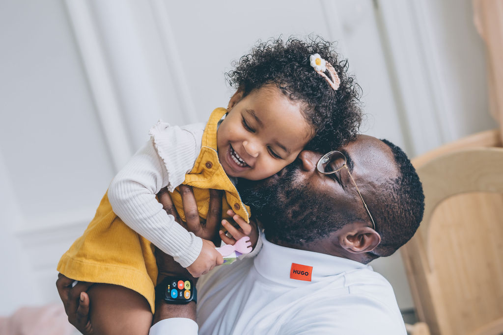 black father kisses happy daughter on cheek