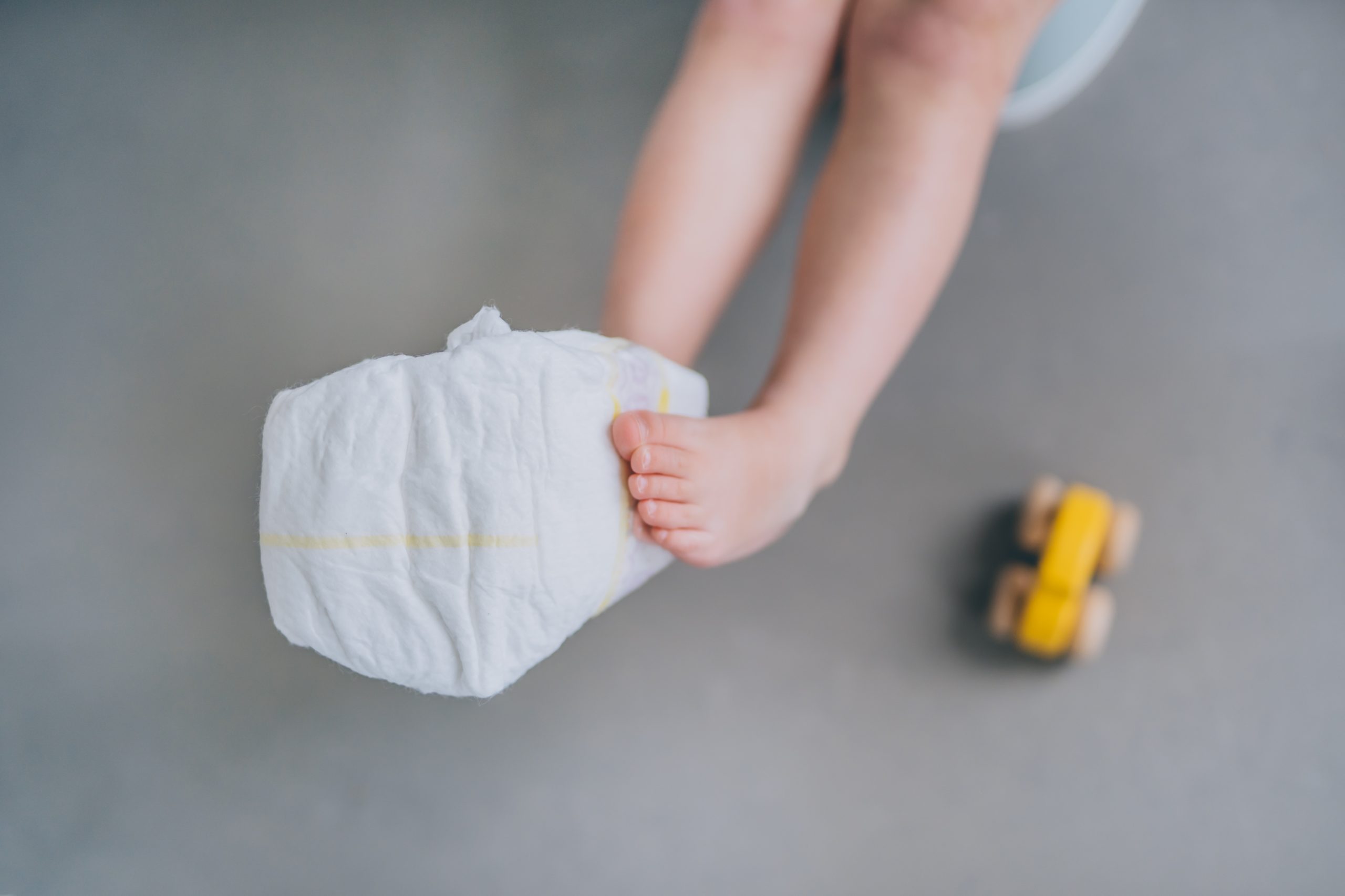 Saving On Expensive Nappy Costs child legs with nappy at their feet with toy