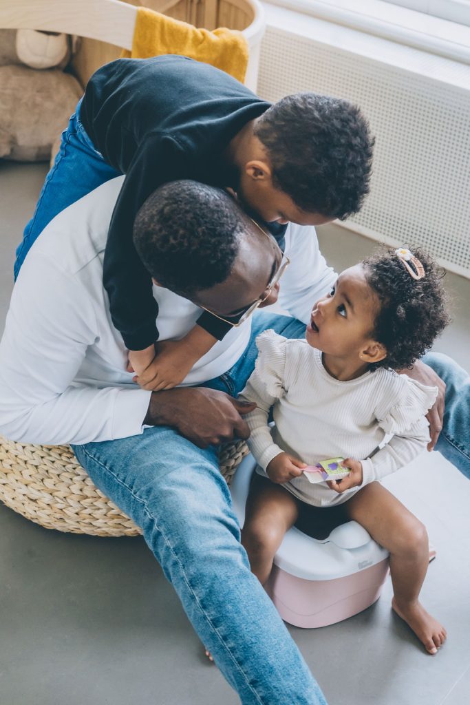 A daddy is potty training his kids. They all seem very happy