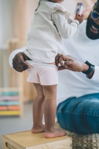 father putting on pants at child. potty training. ready for traveling