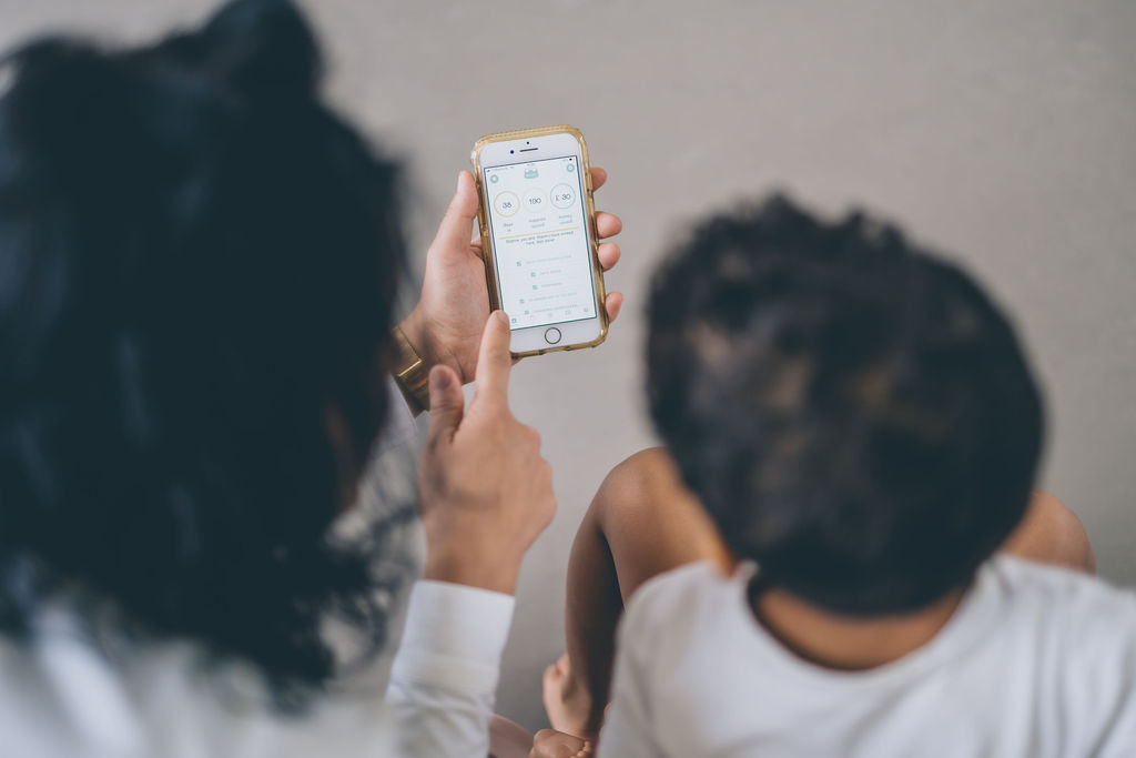 Mother on the left showing child the app on the phone Mother on the left showing child the app on the phone
